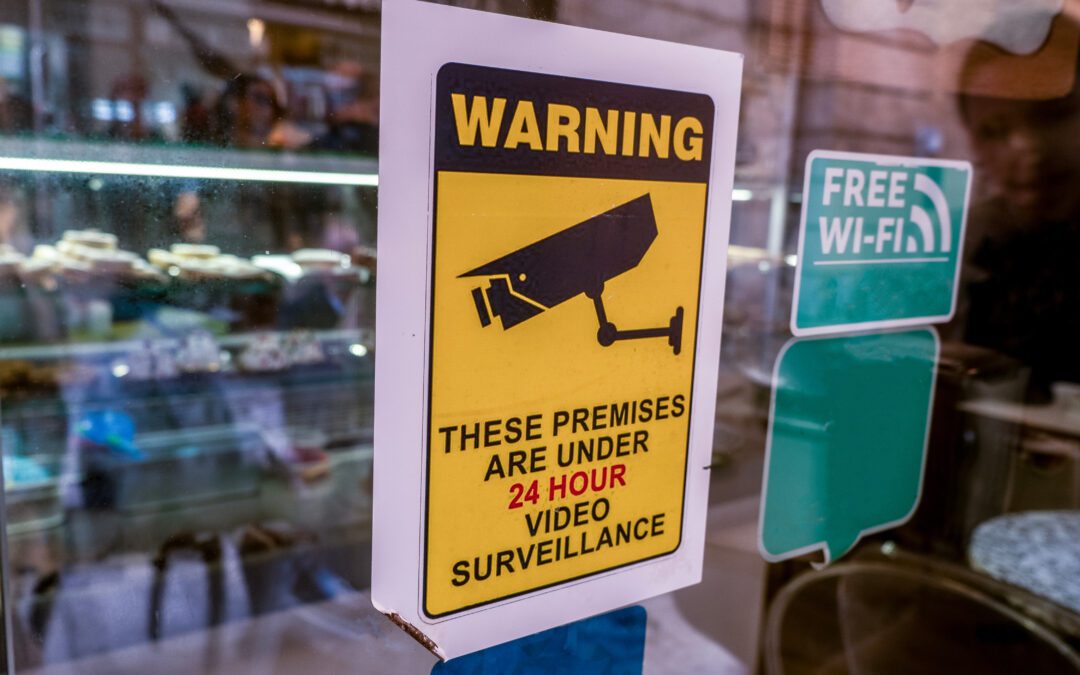 warning sign on business window. sign says "these premises are under 2 4 hour video surveillance"